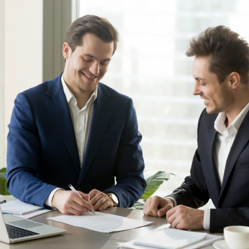 handsome-businessman-signing-contract-with-partner